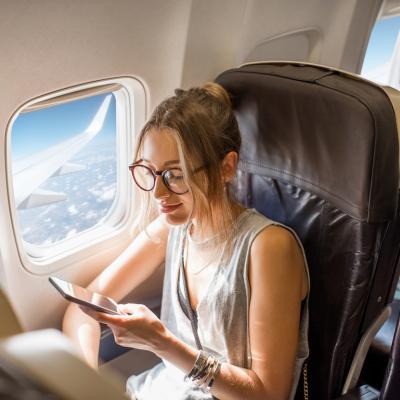 A person holding a phone while seated on an airplane.