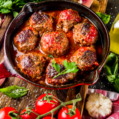 A black skillet of baked Italian meatballs.