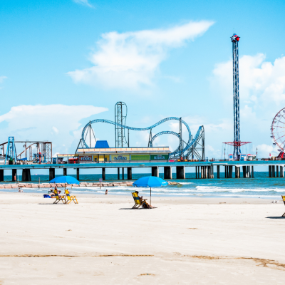 View of beach umbrellas and Pleasure Pier amusement park on Galveston Island, Texas.