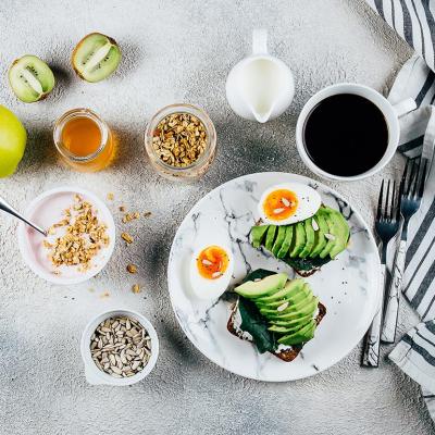 A flat lay photograph of a healthy breakfast concept including eggs, avocado and cup of coffee.