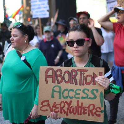 Demonstrator holds a cardboard sign that says "Abortion Access Everywhere" standing with activists for a rally at the Federal Building Plaza in Chicago, Illinois. 