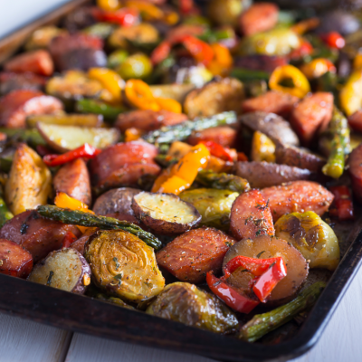 A sheet pan with sausages and roasted vegetables