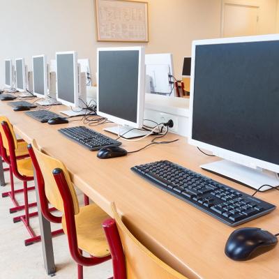 A row of computers and chairs in a school computer lab.