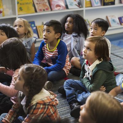 Young students sitting on the floor in a early childhood classroom.