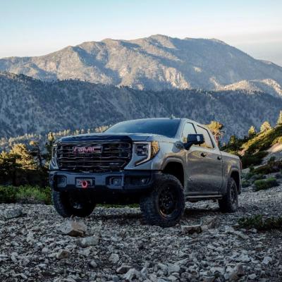 Grey 2023 GMC Sierra 1500 AT4X AEV Edition driving on a rocky hillside.