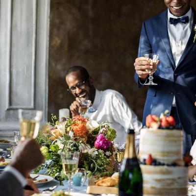 A photograph of a newly-wed couple raising a toast with wedding guests.