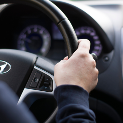 Person's hand on the steering wheel of a Hyundai.