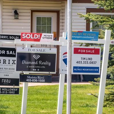 A row of signages are posted for homes for sale in Calgary, Alberta.