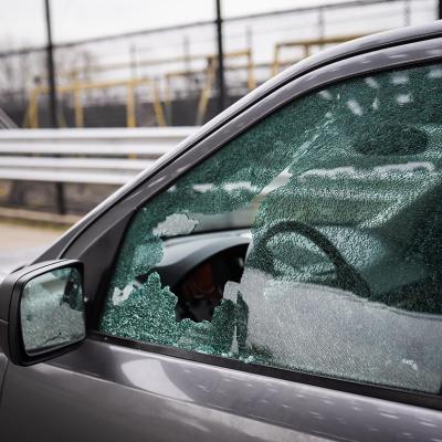 A close-up image of a driver's seat window showing damaged glass from car theft.