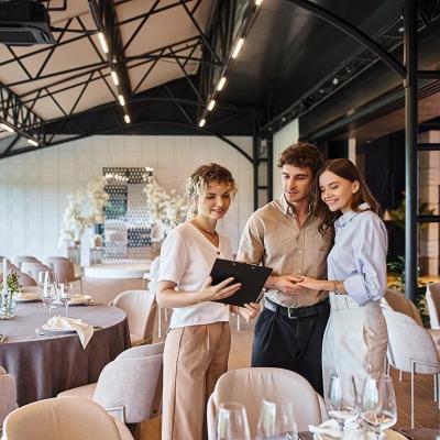 A couple engaging in a discussion with a wedding coordinator inside a wedding venue.