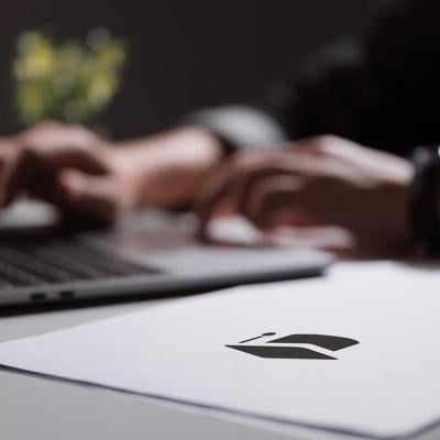 Person working on a laptop computer backlit with paperwork in the foreground.