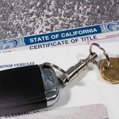 Car keys on top of DMV and certificate of title documents from the State of California.