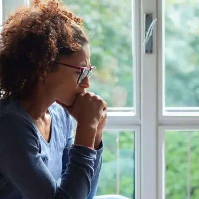 Woman sitting by a window looking worried