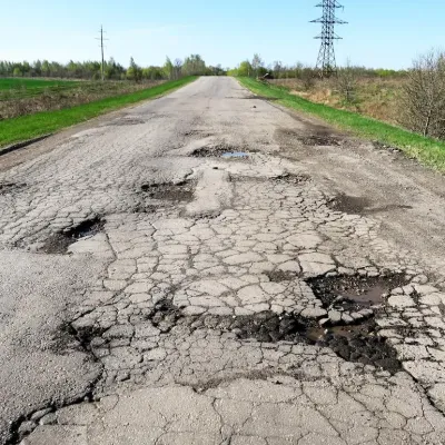 Damaged road with cracked asphalt and potholes