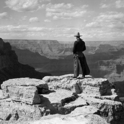 A cowboy wearing chaps stands on Grandeur Point, East Rim Drive, overlooking the Grand Canyon, Arizona, circa 1935. 