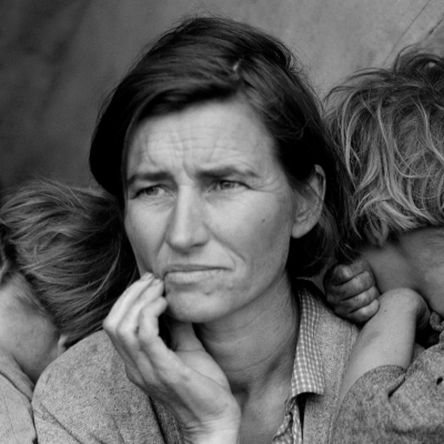 A migrant mother looks worried as her two children lean on her shoulders