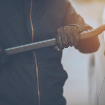 Person using crowbar to break into car.