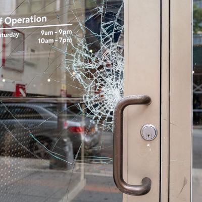 A store's glass door is cracking from damage.