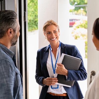 A female entrepreneur happily greeting a couple inside their home.