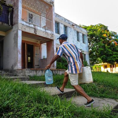 A man walks up concrete steps carrying plastic jugs of water in the Consolacion del Sur neighborhood in the Pinar del Rio province, Cuba.