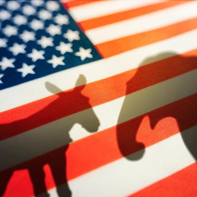 Silhouette of donkey and elephant seen through American flag as concept of Democrats vs Republicans.