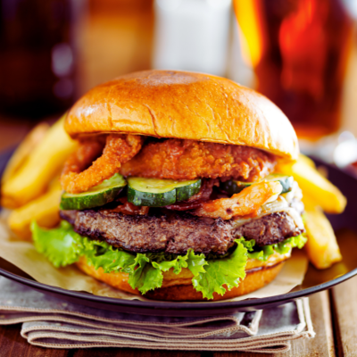 Burger loaded with onion rings and pickles.