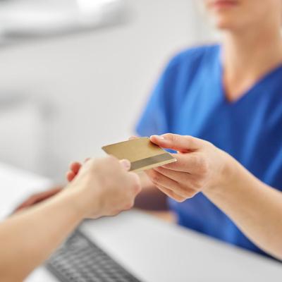 Close up of a person handing a credit card to a pay at a medical office. 