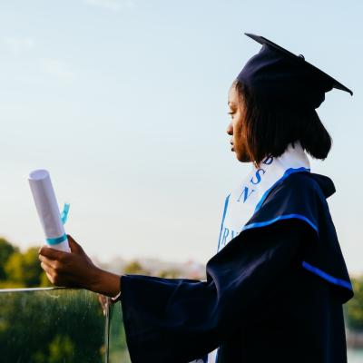 Portrait of college graduate holding a diploma and looking into the distance.