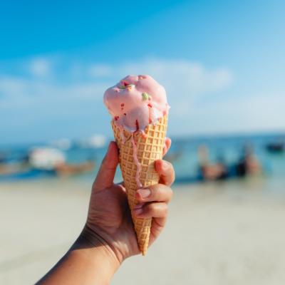 Hand holding ice cream cone at the beach in summer.