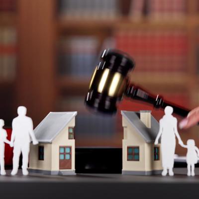 A cut-out illustration of a family of four and a house are divided by an attorney's gavel.