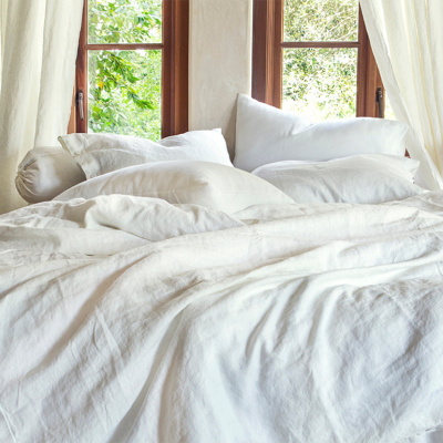 A queen size bed laid cozily with white linen sheets.