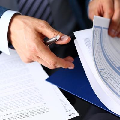 Close up of hands of person wearing a suit shuffling insurance forms and holding a pen.