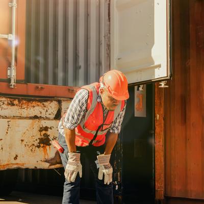 An African-American male container port worker appears tired and dizzy from intense heat.