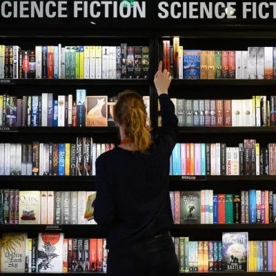 A person browses a big selection of sci-fi books at the store.