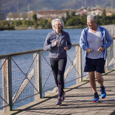 Active senior couple jogging together on a bridge