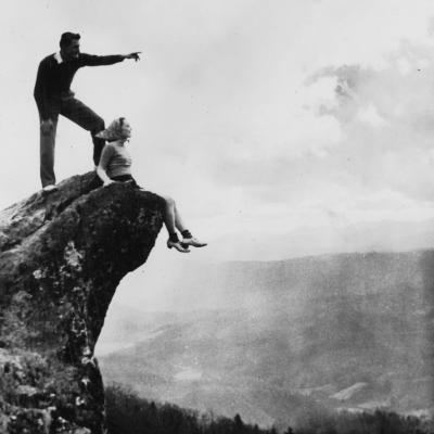 Perched atop Blowing Rock, an unidentified couple as they look out over Great Smoky Mountains National Park, North Carolina, circa 1930.