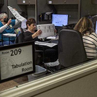 Clerk election specialists prepare to feed ballots into the tabulator/scanner at the Shasta County Clerk & Elections office in Redding in 2022.