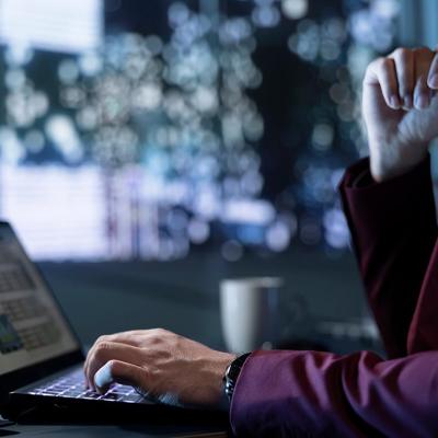 Person looks at finance data on laptop with abstract background suggesting concept of technology and future.