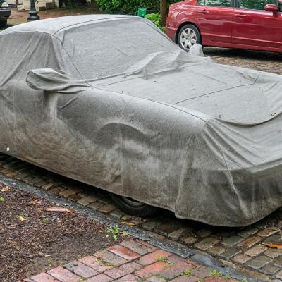 A car covered by a grey tarpaulin.