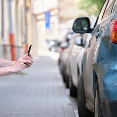 A man taking a photo of his damaged car caused by a hit-and-run.