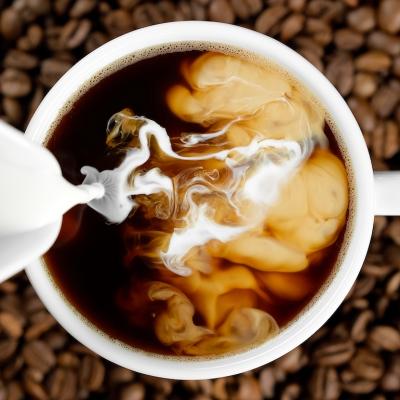 Pouring milk in coffee cup.