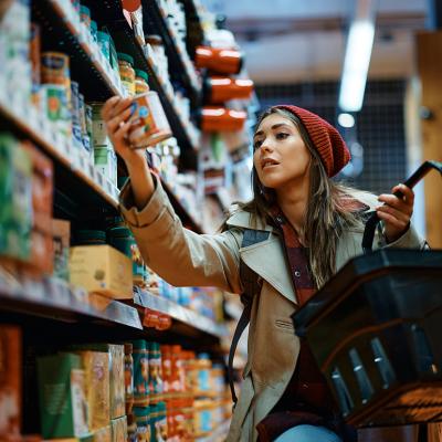 A young woman carefully selecting items to purchase in a grocery aisle.