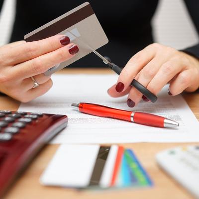 A woman cutting one of her credit cards in half.