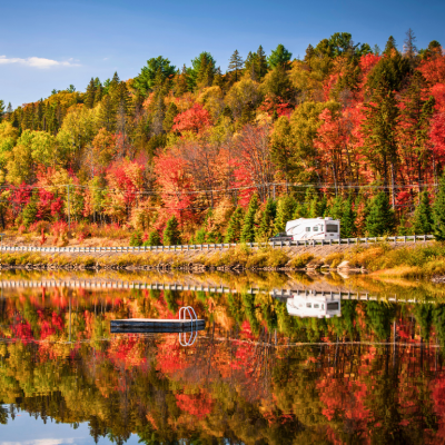 RV on road with fall foliage in the background.