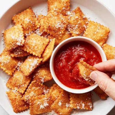 St. Louis toasted ravioli served on a plate with red dipping sauce.