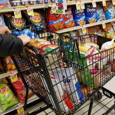 Pushing a cart filled with groceries on the snacks aisle inside a supermarket in Wilmington, Delaware.