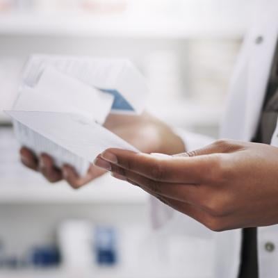 A medical professional looking through drugs and their descriptions in a laboratory.