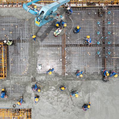 An aerial view of construction workers pouring concrete for a project site.