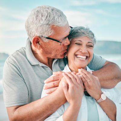 Happy retired couple embrace on the beach.