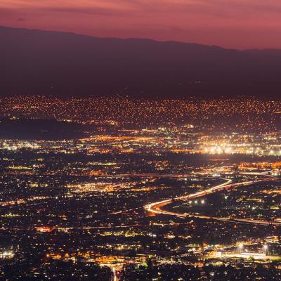 Panoramic night view of urban sprawl in San Jose, Silicon Valley, California; Visible light trail left by cars driving on one of the freeways.